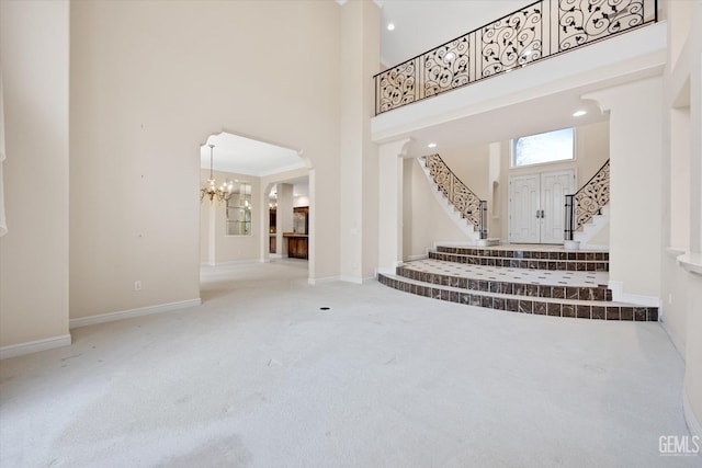 interior space with carpet floors, ornamental molding, a high ceiling, and an inviting chandelier