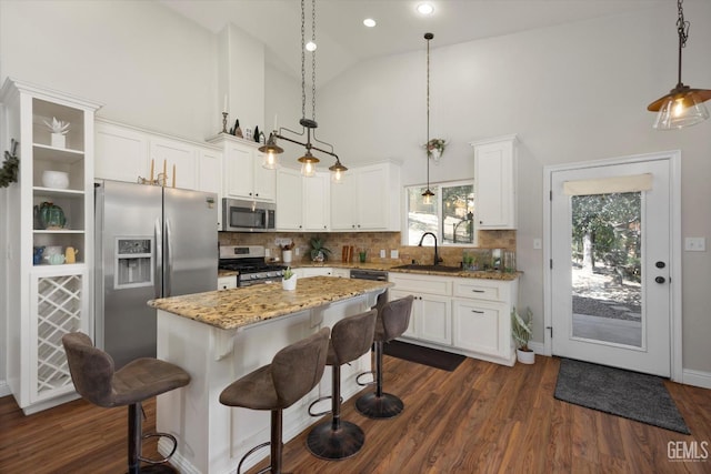 kitchen featuring light stone countertops, a center island, hanging light fixtures, and appliances with stainless steel finishes