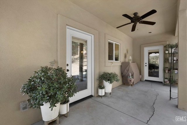 view of exterior entry featuring ceiling fan and a patio