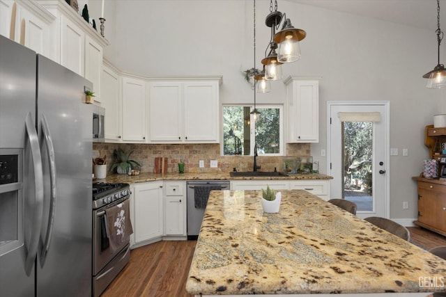 kitchen featuring decorative backsplash, appliances with stainless steel finishes, sink, white cabinets, and a center island