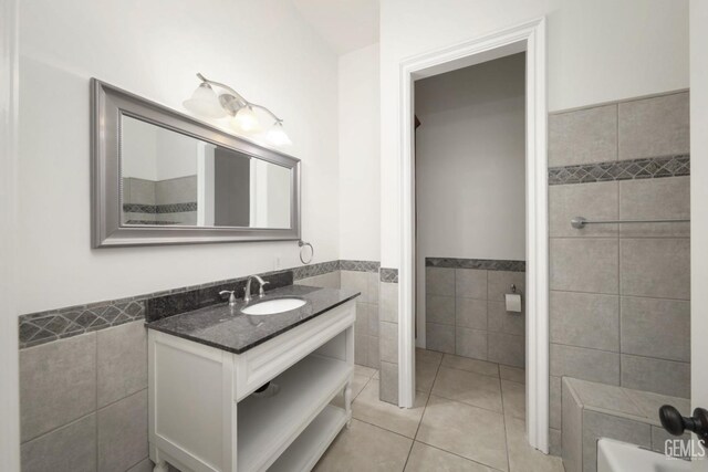 bathroom featuring tile patterned floors, vanity, a bathing tub, and tile walls