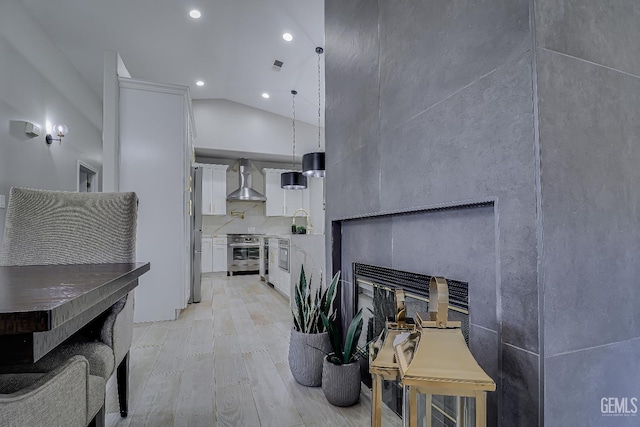 6800 Eagle Cap St, Bakersfield, CA 93313 - living room with a glass covered fireplace, vaulted ceiling, light wood-style flooring, and recessed lighting