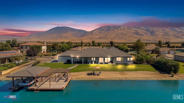 pool at dusk featuring a yard, a water and mountain view, and a boat dock