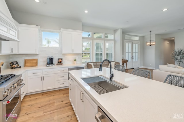 kitchen with pendant lighting, white cabinetry, high end stainless steel range oven, and sink