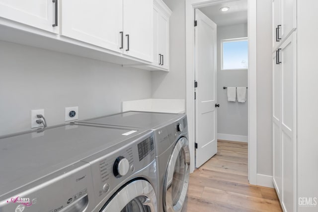 clothes washing area featuring cabinets, washing machine and dryer, and light hardwood / wood-style flooring