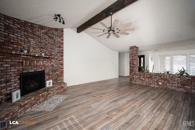 unfurnished living room featuring a brick fireplace, hardwood / wood-style flooring, vaulted ceiling with beams, and a textured ceiling