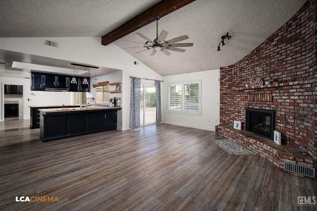 unfurnished living room with dark hardwood / wood-style flooring, ceiling fan, a fireplace, and a textured ceiling