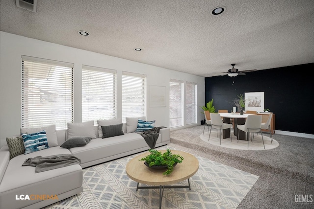 carpeted living room with ceiling fan and a textured ceiling