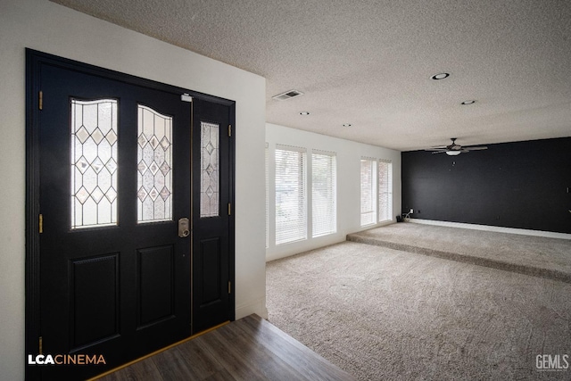 entryway with ceiling fan, carpet floors, and a textured ceiling