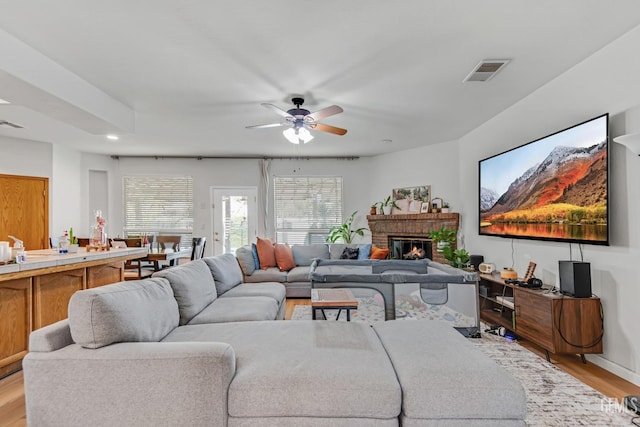 11602 Marazion Hill Ct, Bakersfield, CA 93311 - living room featuring a ceiling fan, a fireplace, light wood-type flooring, baseboards, and visible vents