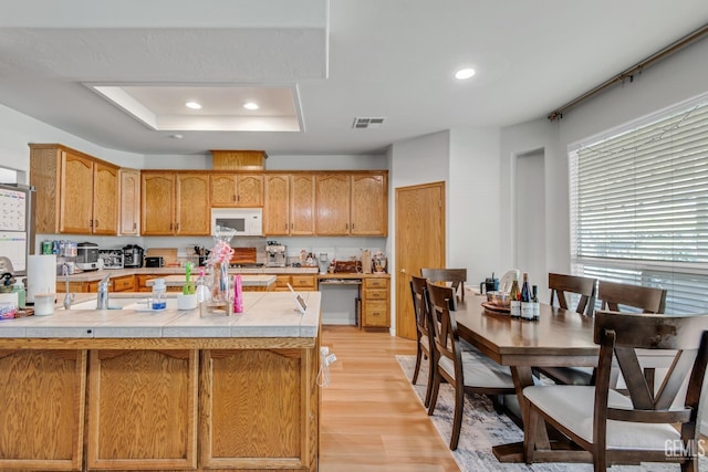 11602 Marazion Hill Ct, Bakersfield, CA 93311 - kitchen featuring visible vents, tile counters, white microwave, light wood-style floors, and a tray ceiling