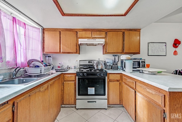 kitchen with kitchen peninsula, gas stove, light tile patterned floors, and sink