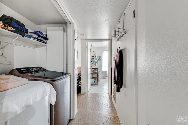 washroom featuring light tile patterned floors, a textured ceiling, and washer and clothes dryer