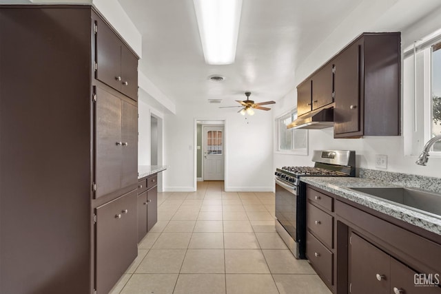 kitchen featuring light stone countertops, sink, ceiling fan, stainless steel range with gas cooktop, and light tile patterned floors