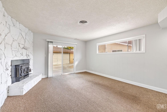 unfurnished living room featuring a wood stove and a textured ceiling