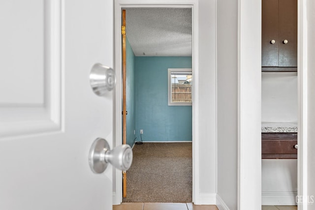 hallway featuring a textured ceiling and light carpet