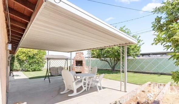 view of patio with an outdoor fireplace, a fenced backyard, and outdoor dining space