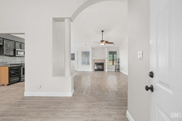 12017 Hannah Denise Ave, Bakersfield, CA 93312 - unfurnished living room with a ceiling fan, a fireplace, light wood finished floors, arched walkways, and lofted ceiling