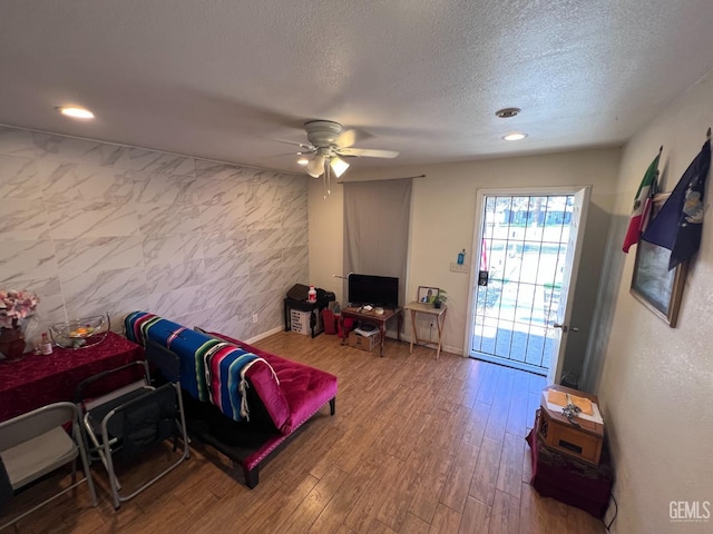 living room with hardwood / wood-style floors, a textured ceiling, and ceiling fan