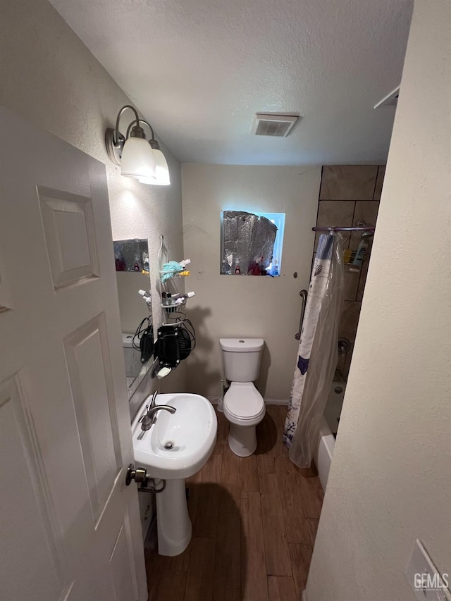 full bathroom featuring sink, toilet, shower / bathtub combination with curtain, a textured ceiling, and wood-type flooring