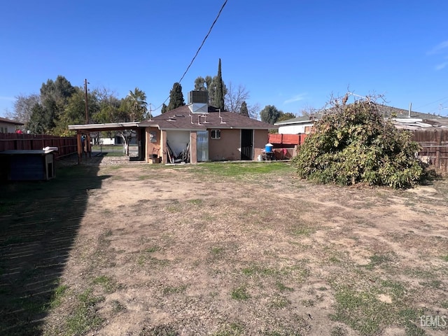 back of property with a carport, a lawn, and central air condition unit