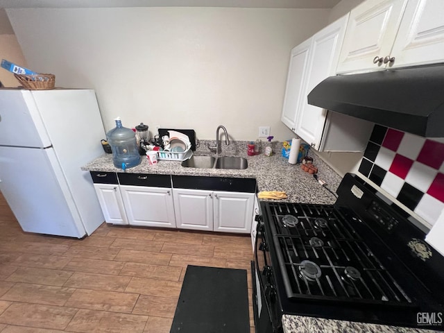 kitchen featuring light stone countertops, black range with gas stovetop, sink, white refrigerator, and white cabinets