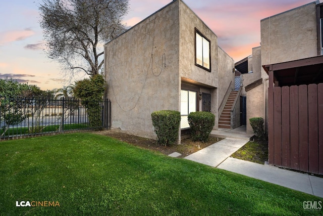 view of front facade featuring stairway, a front yard, fence, and stucco siding