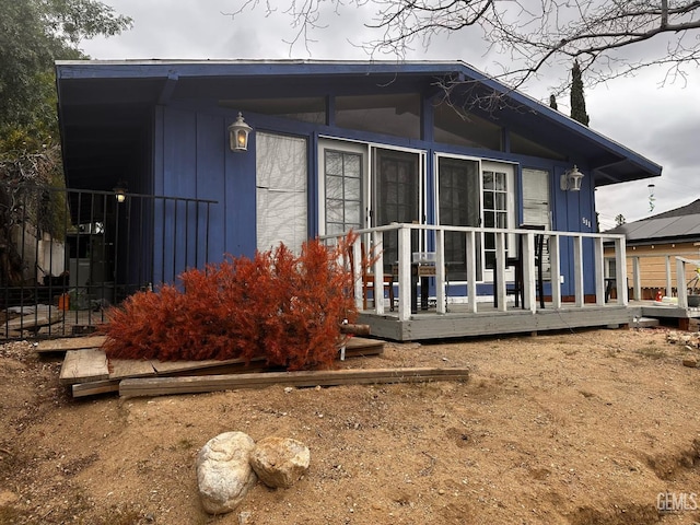 view of property exterior featuring a sunroom and a deck