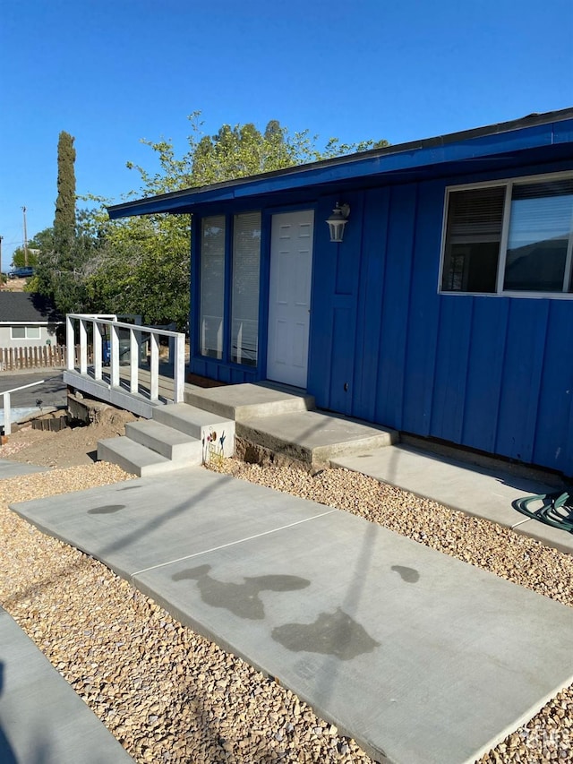 entrance to property with board and batten siding and a patio