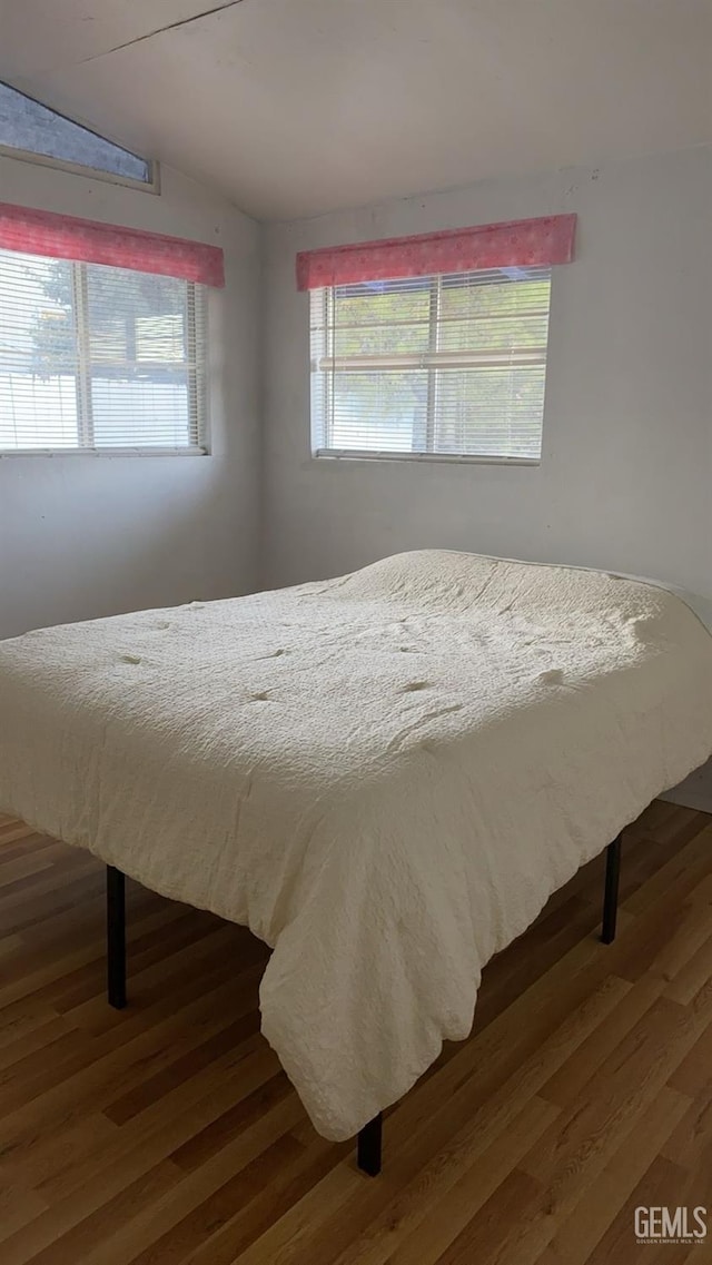 bedroom with wood finished floors and lofted ceiling