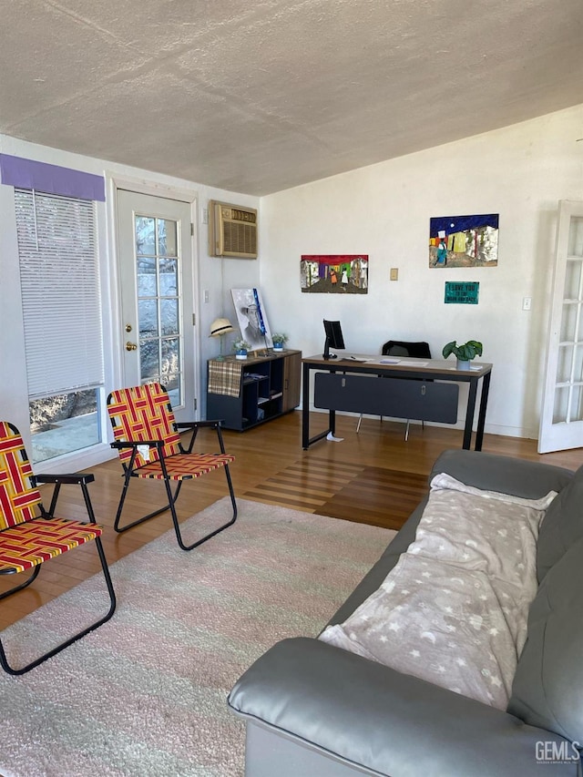 living area featuring a wall mounted air conditioner, a textured ceiling, and wood finished floors