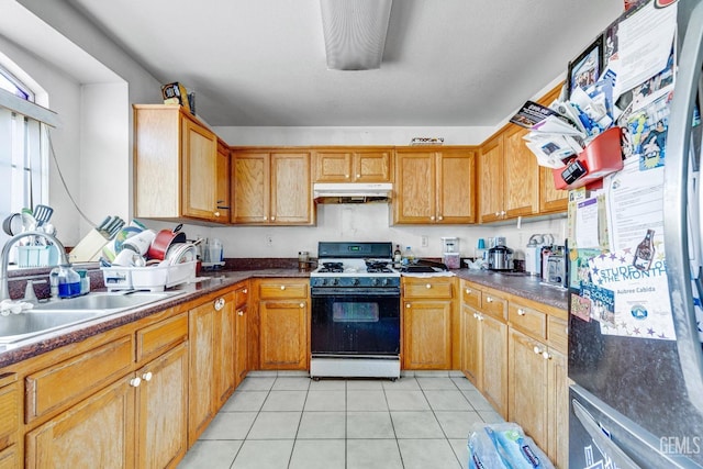 kitchen featuring light tile patterned flooring, gas stove, stainless steel refrigerator, and sink