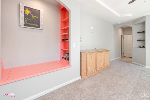 corridor featuring built in shelves and light carpet