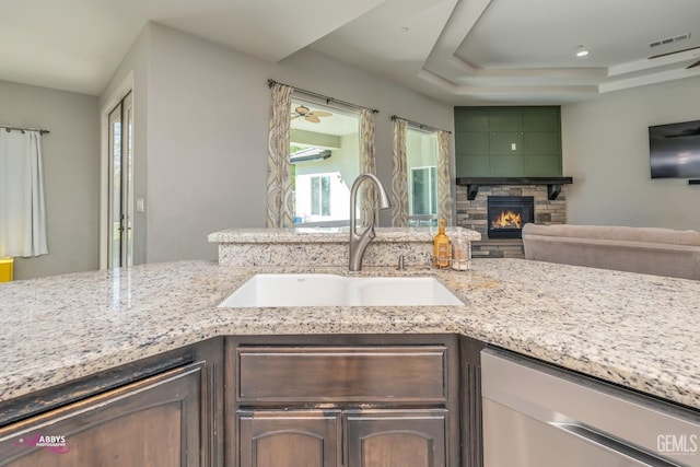 kitchen with a fireplace, dishwasher, dark brown cabinetry, and sink