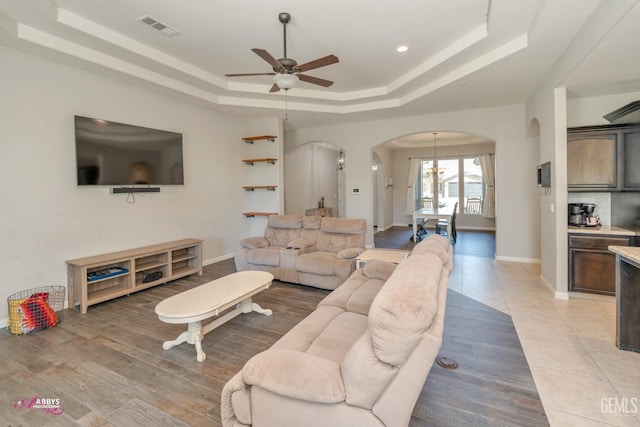 living room featuring a tray ceiling and ceiling fan