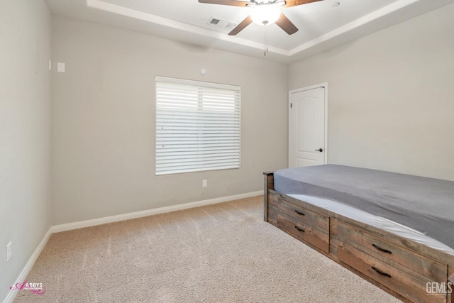 carpeted bedroom with a tray ceiling and ceiling fan