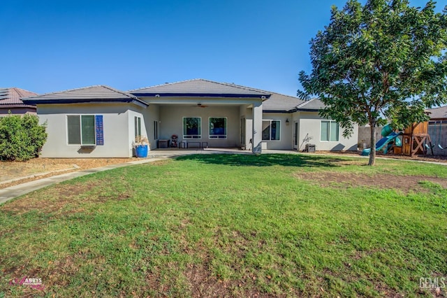 rear view of property with a playground, ceiling fan, a patio area, and a yard