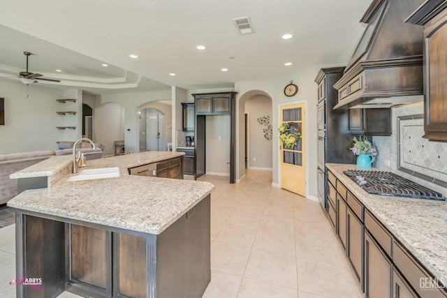 kitchen featuring appliances with stainless steel finishes, backsplash, light stone counters, custom exhaust hood, and a large island