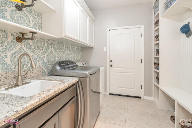 laundry room featuring washing machine and dryer, sink, light tile patterned flooring, and cabinets