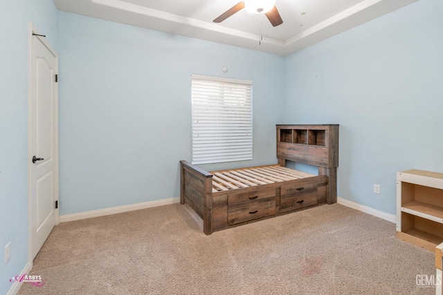 carpeted bedroom featuring a raised ceiling and ceiling fan