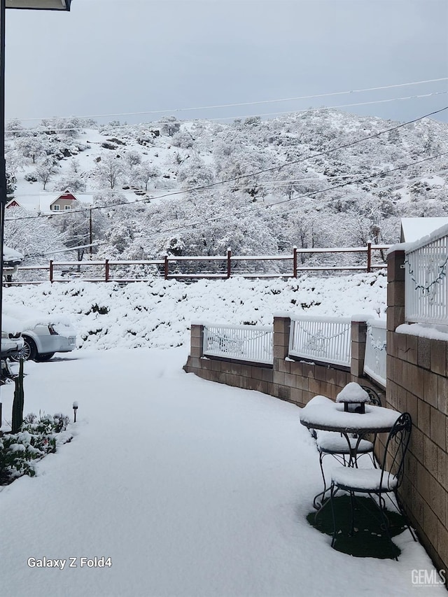 snowy yard featuring a mountain view and fence