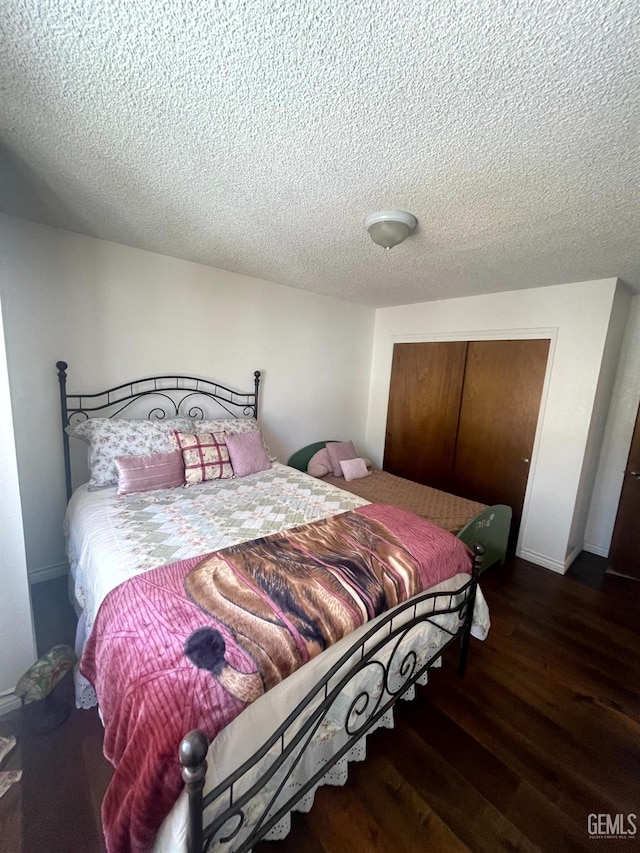 bedroom with a textured ceiling, baseboards, a closet, and wood finished floors