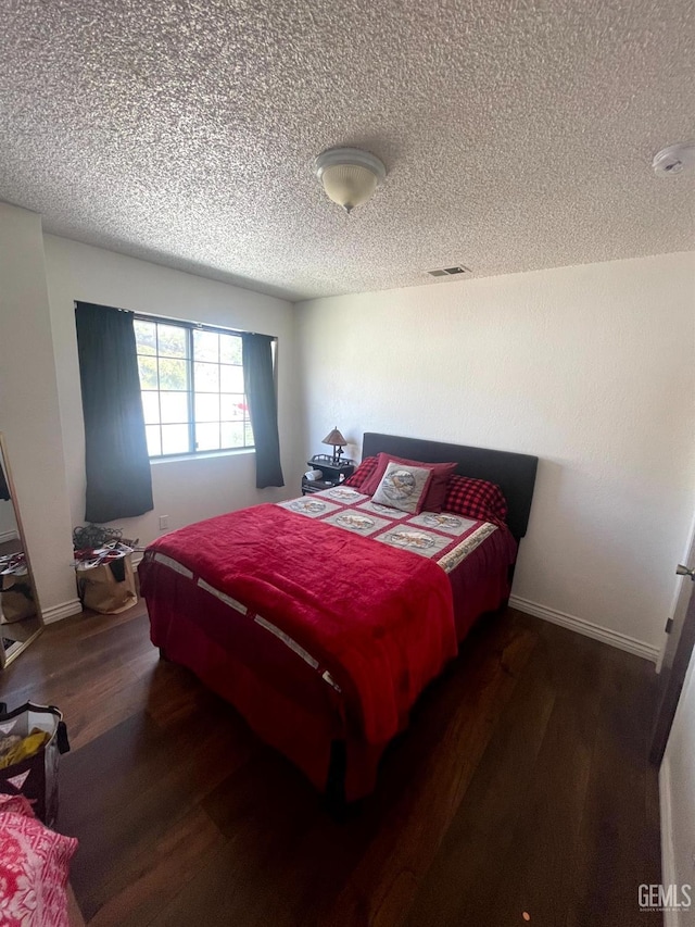 bedroom featuring a textured ceiling, baseboards, wood finished floors, and visible vents