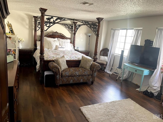 bedroom featuring a textured ceiling, visible vents, and wood finished floors