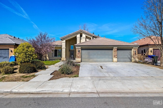 view of front of property with stucco siding, driveway, stone siding, an attached garage, and a tiled roof