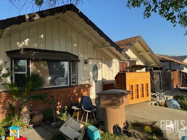 back of house with board and batten siding, brick siding, and fence