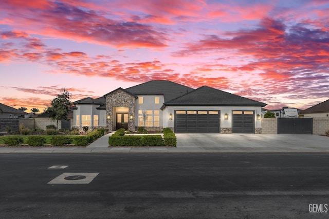 view of front of house featuring stone siding, concrete driveway, an attached garage, and stucco siding