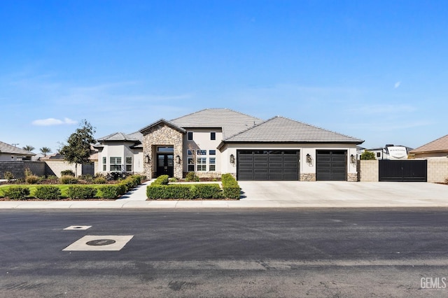 french country inspired facade with an attached garage, fence, stone siding, driveway, and stucco siding