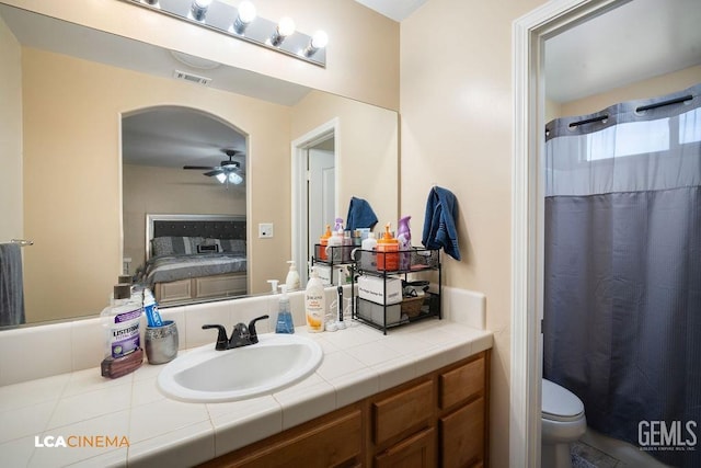 ensuite bathroom with visible vents, curtained shower, connected bathroom, ceiling fan, and vanity