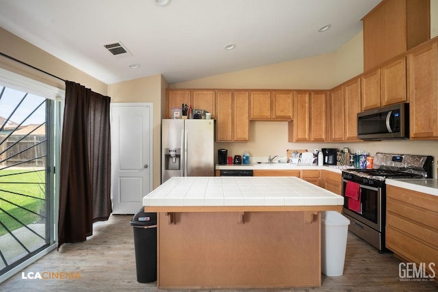 kitchen with tile countertops, a kitchen island, visible vents, and stainless steel appliances